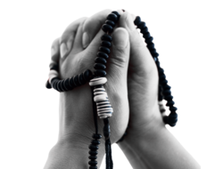 a pair of brown hands in a prayer with beads